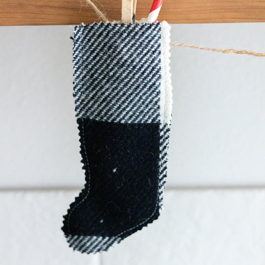 Black and white checkered stocking with a red and white striped straw on a wooden surface.