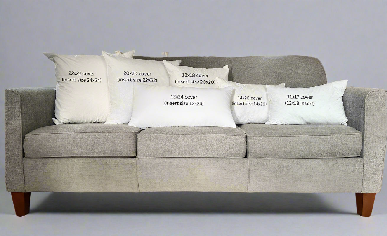 Gray sofa with decorative pillows displaying measurements in a living room setting.