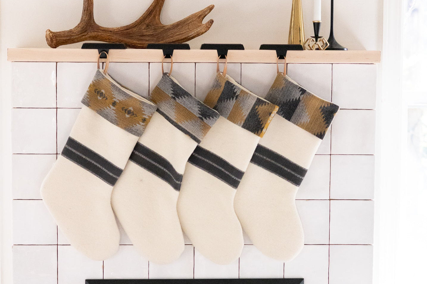 Four stockings hanging above a fireplace with tiled wall and sofa in the background
