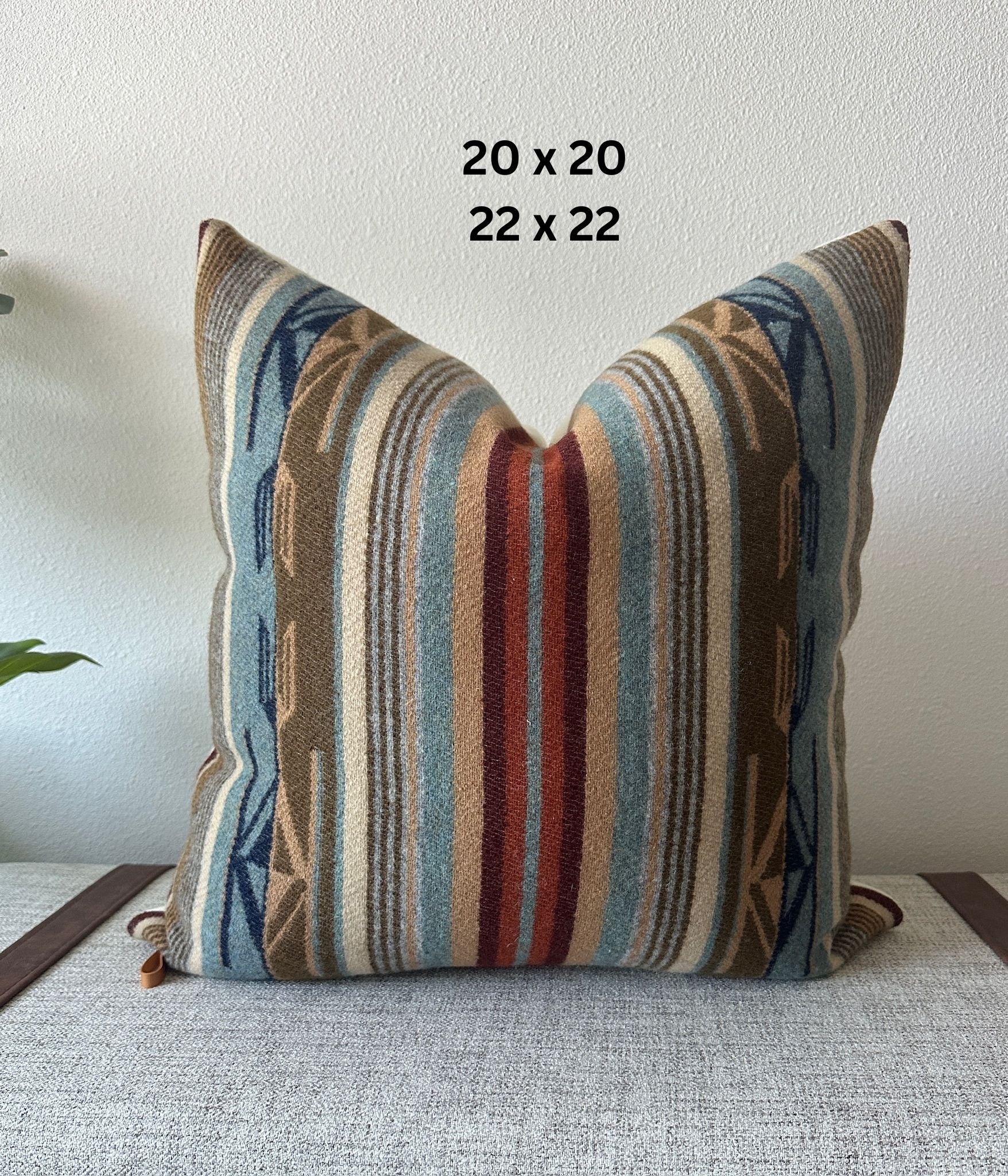 Decorative pillow with striped pattern on a light surface, with dimensions 20 x 20 and 22 x 22 displayed.