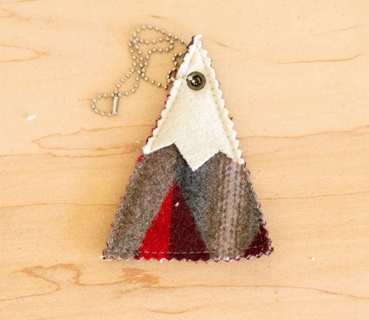 Triangular pendant with mountain design on a wooden surface