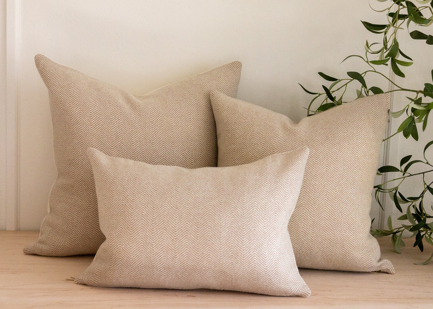 Beige textured cushions on a wooden surface with a plant in the background