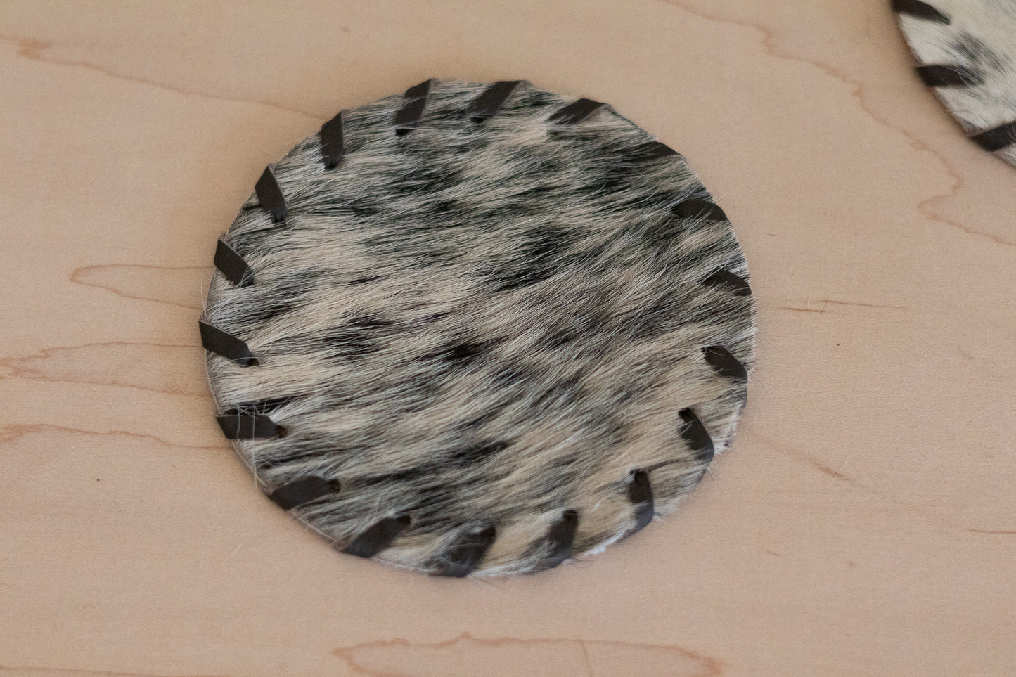 Round fur-like material with black and gray pattern on a beige surface