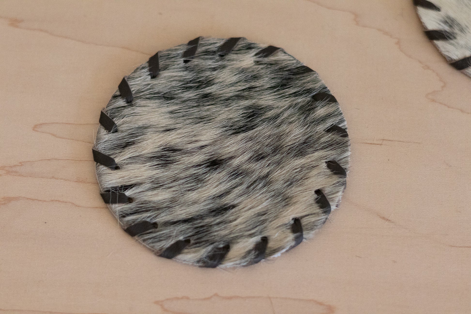 Round fur-like material with black and gray pattern on a beige surface