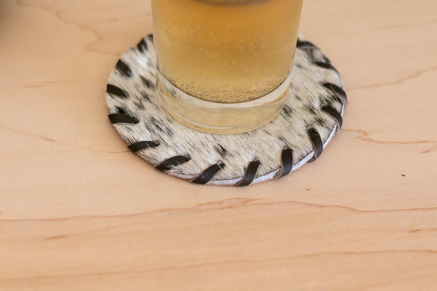 Glass of beer on a animal print coaster on a wooden surface