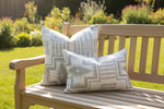 Gray patterned pillows on a wood  bench with a sunny background