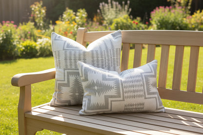 Gray patterned pillows on a wood  bench with a sunny background