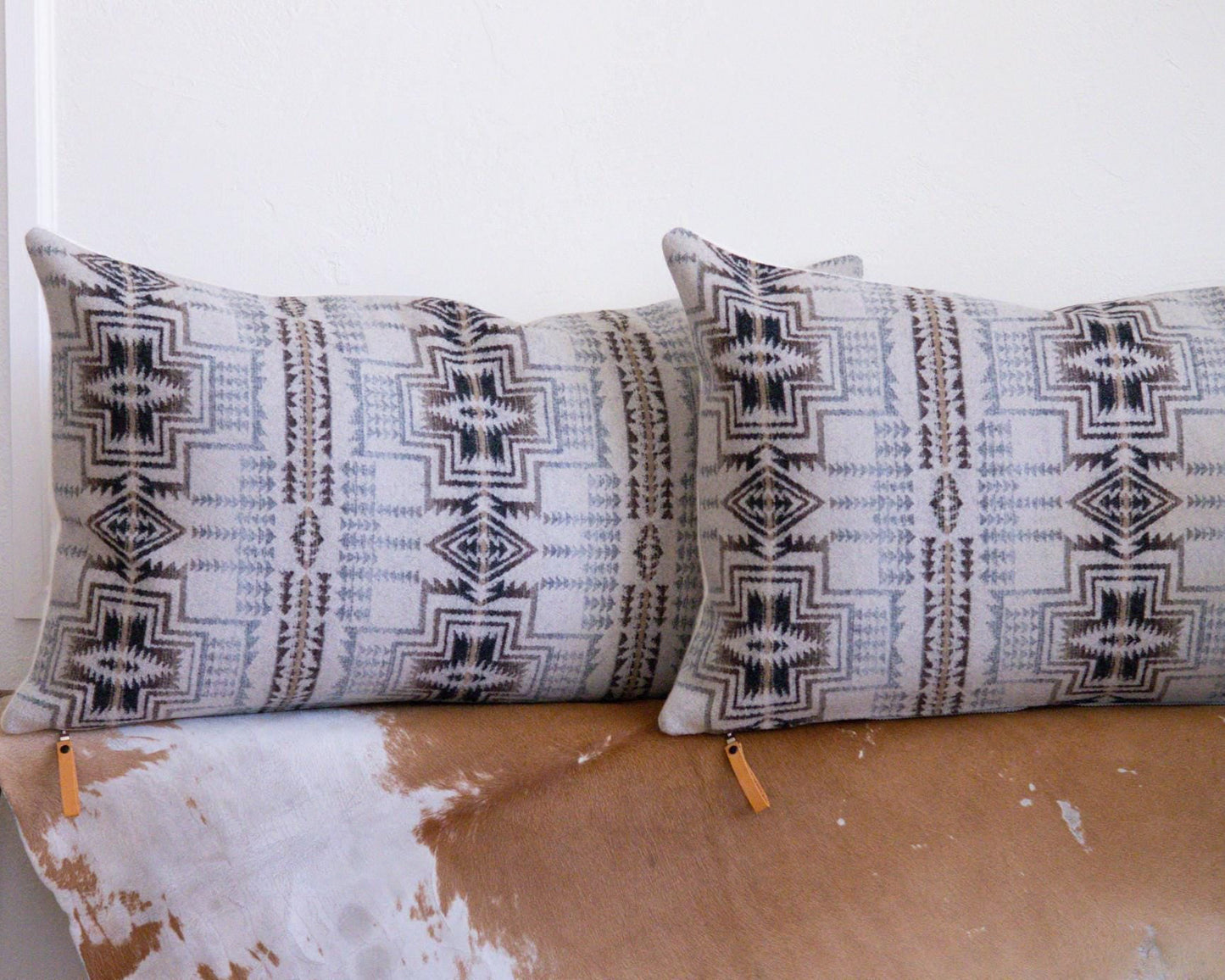 Two patterned Pendleton® pillows on a wooden surface with a white background
