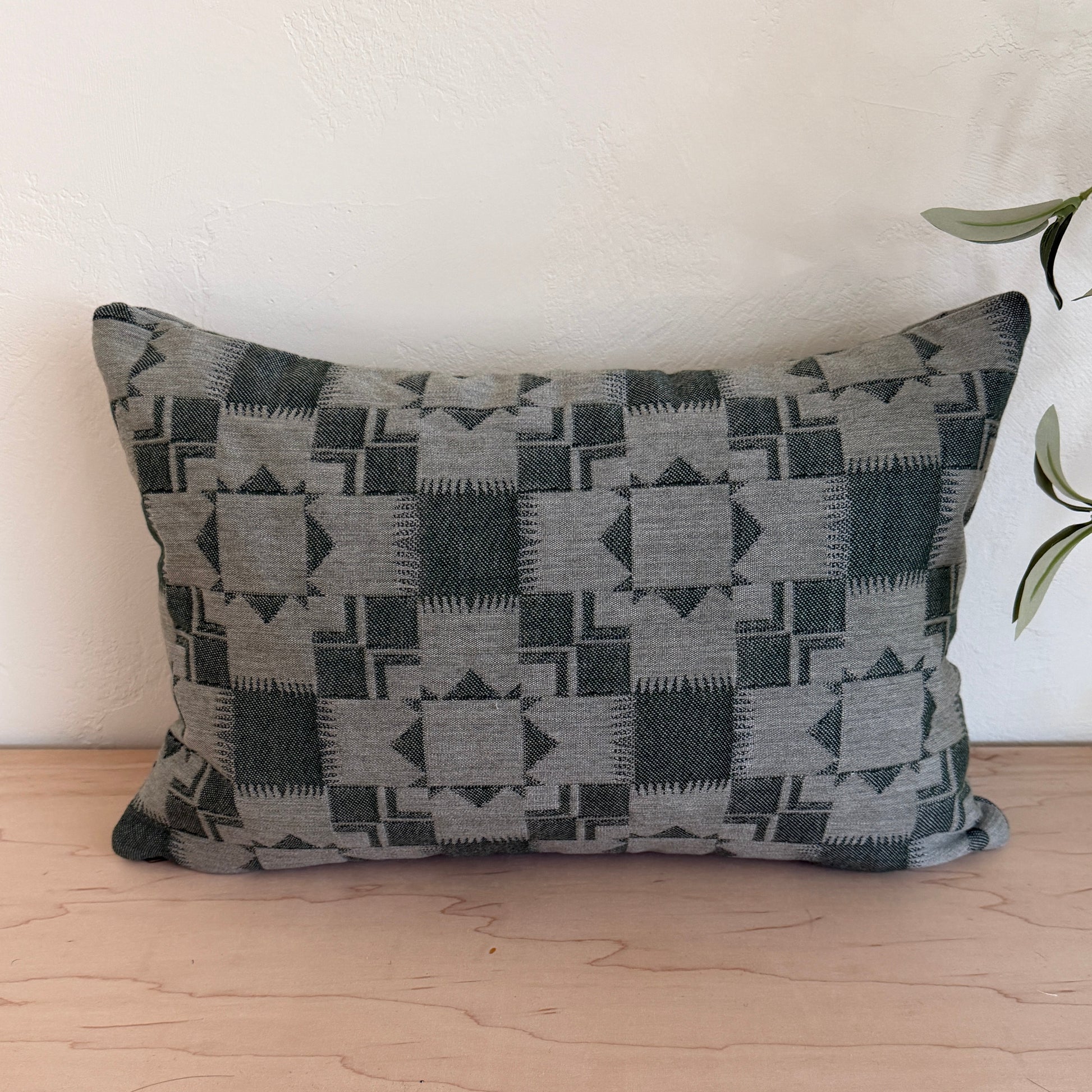 Decorative pillow with geometric pattern on a white couch next to a wooden wall.