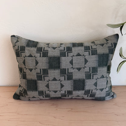 Decorative pillow with geometric pattern on a white couch next to a wooden wall.
