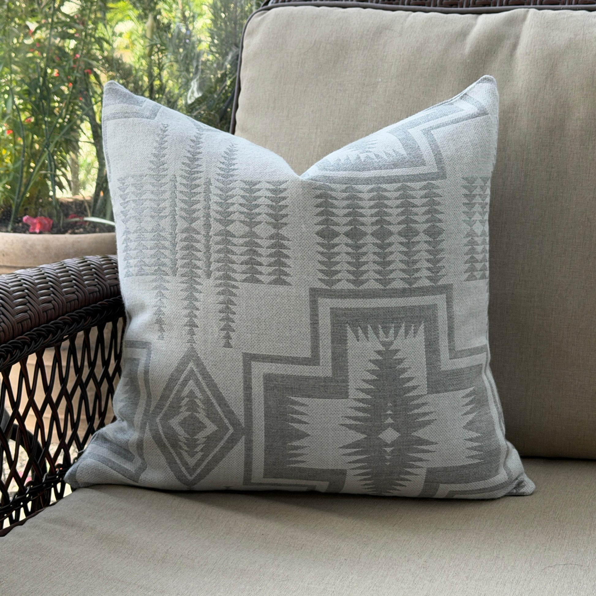 Decorative pillow with geometric pattern on a beige couch outdoors.