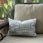Decorative pillow with geometric pattern on a beige cushion outdoors.
