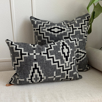 Two patterned pillows on a light-colored sofa