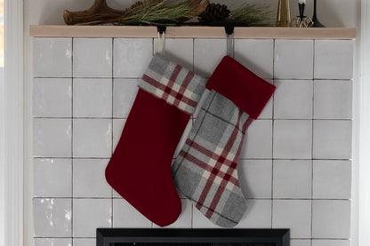 Red and gray plaid stockings hanging above a fireplace with decorative antlers on the mantel.