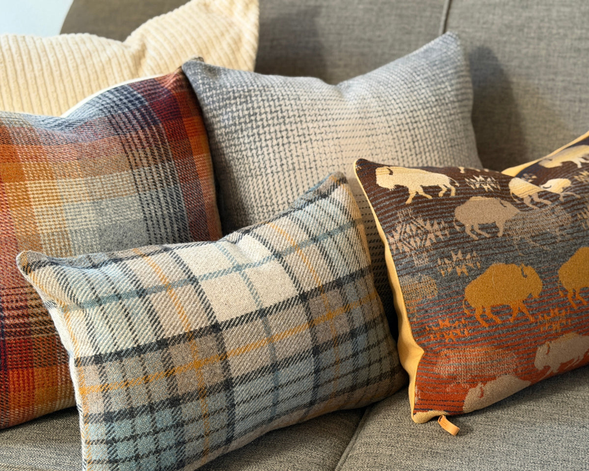 Merced and Misty Ridge plaid pillow styled with plaid and bison print pillows on a gray sofa