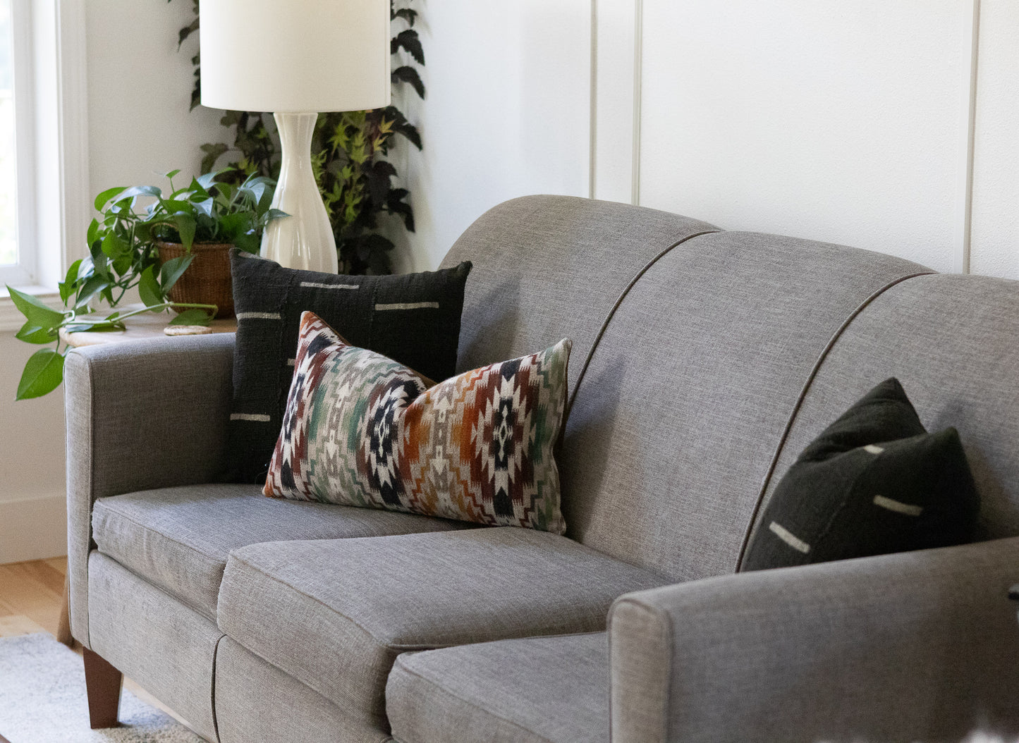 Gray sofa with patterned and solid color pillows in a living room setting.