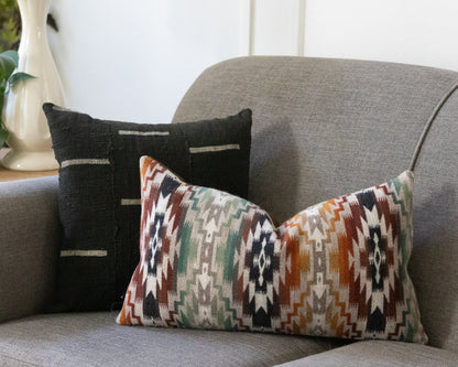 Decorative pillows on a gray sofa with a plant and vase in the background