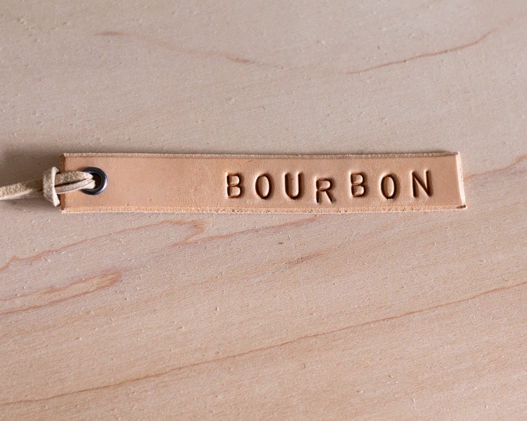 Leather tag with 'BOURBON' engraving on a wooden surface