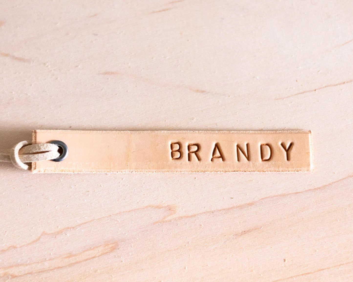 Leather tag with 'BRANDY' engraved on a beige background