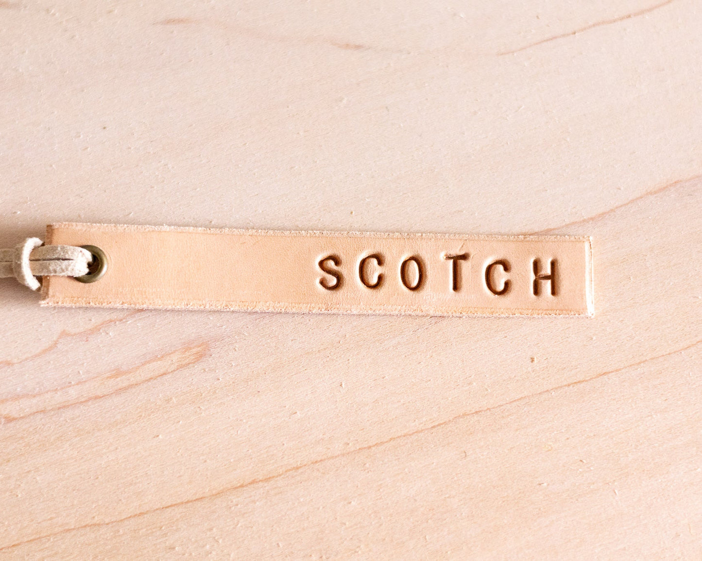 Leather tag with 'SCOTCH' engraving on a wood background