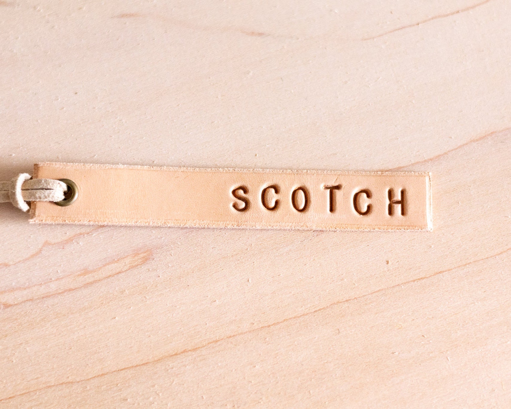Leather tag with 'SCOTCH' engraving on a wood background