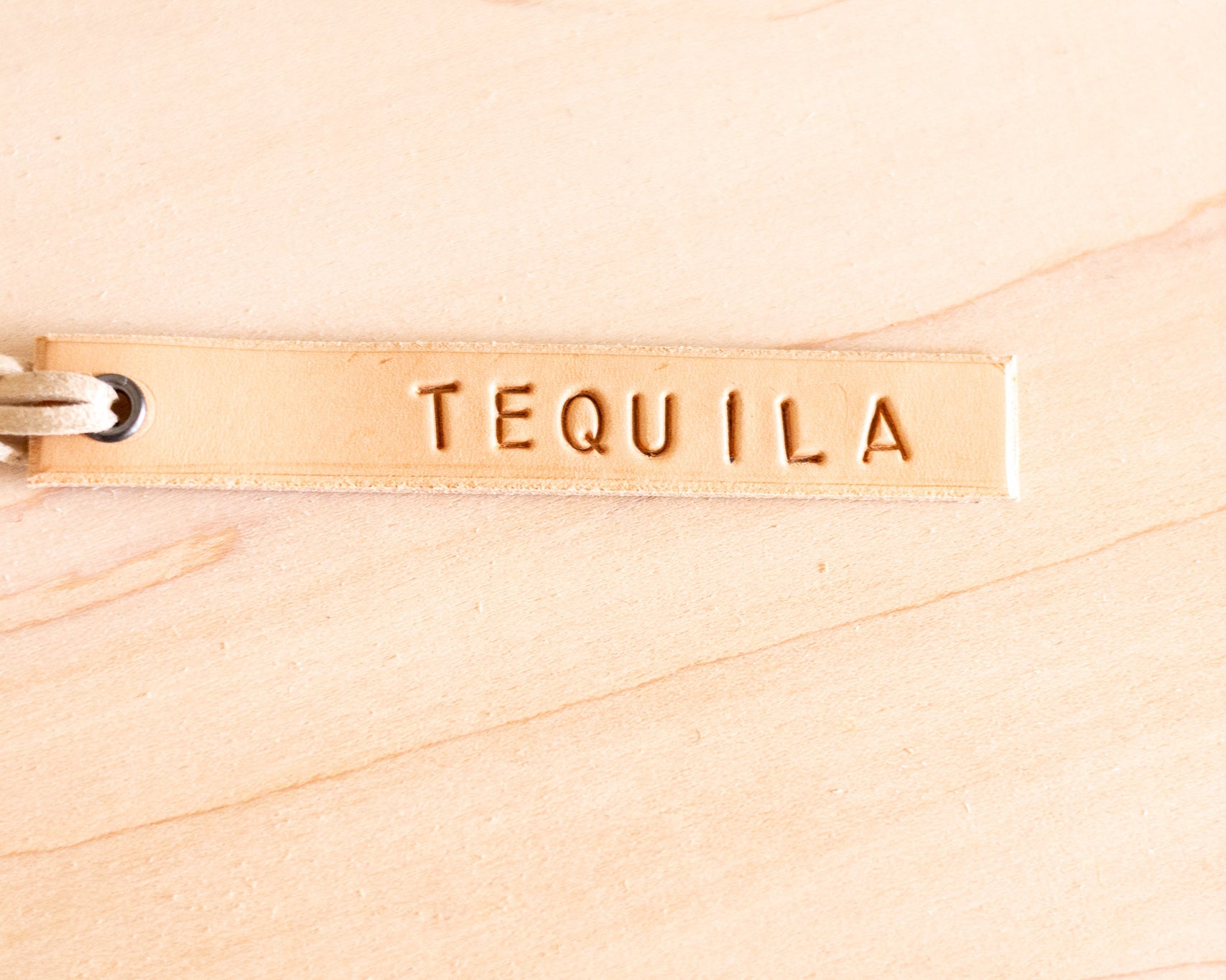 Leather tag with 'TEQUILA' engraved on a wood background