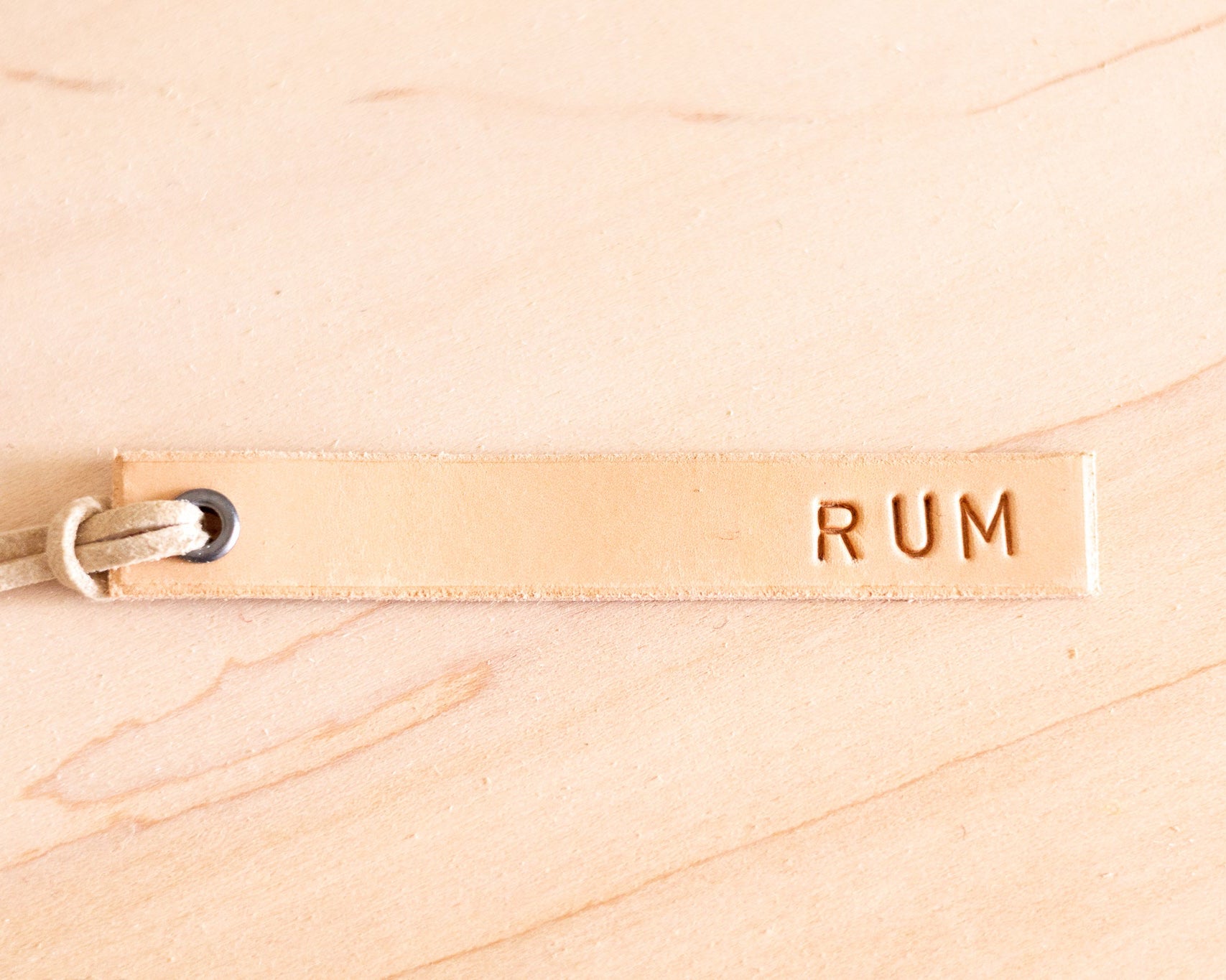 Leather tag with 'RUM' text on a wooden surface