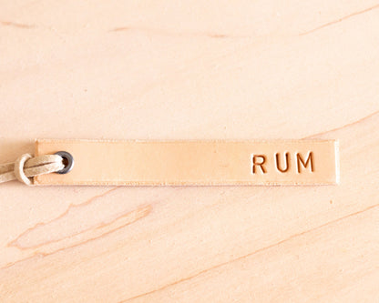 Leather tag with 'RUM' text on a wooden surface