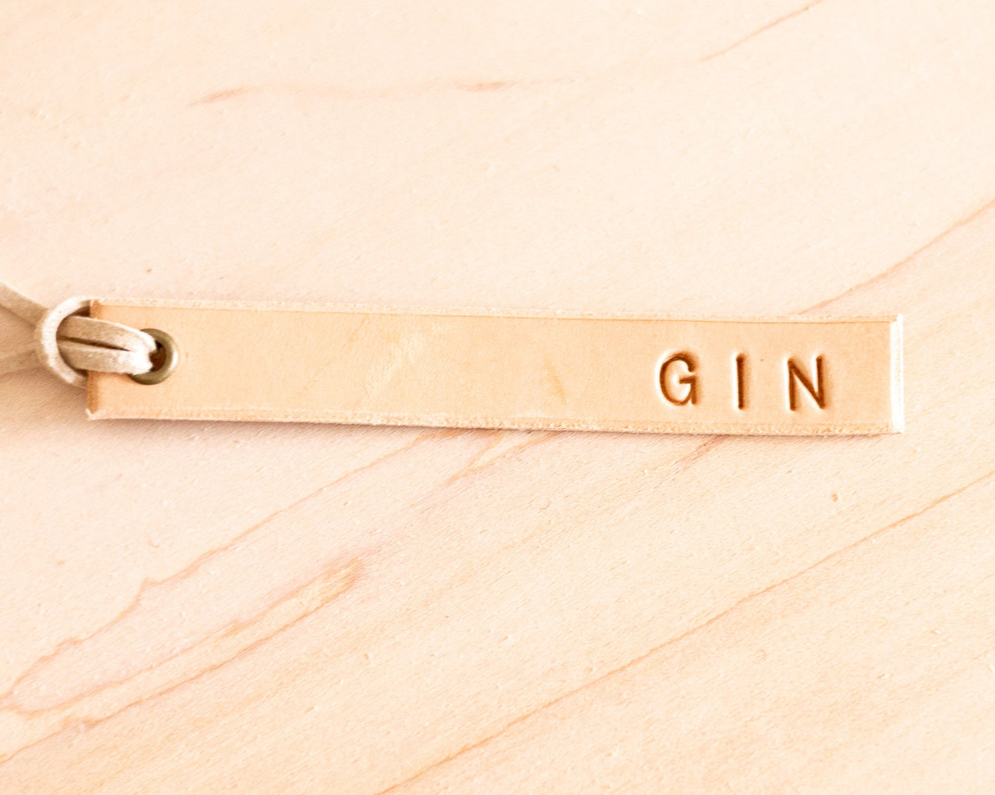 Leather 'GIN' tag on a wood background