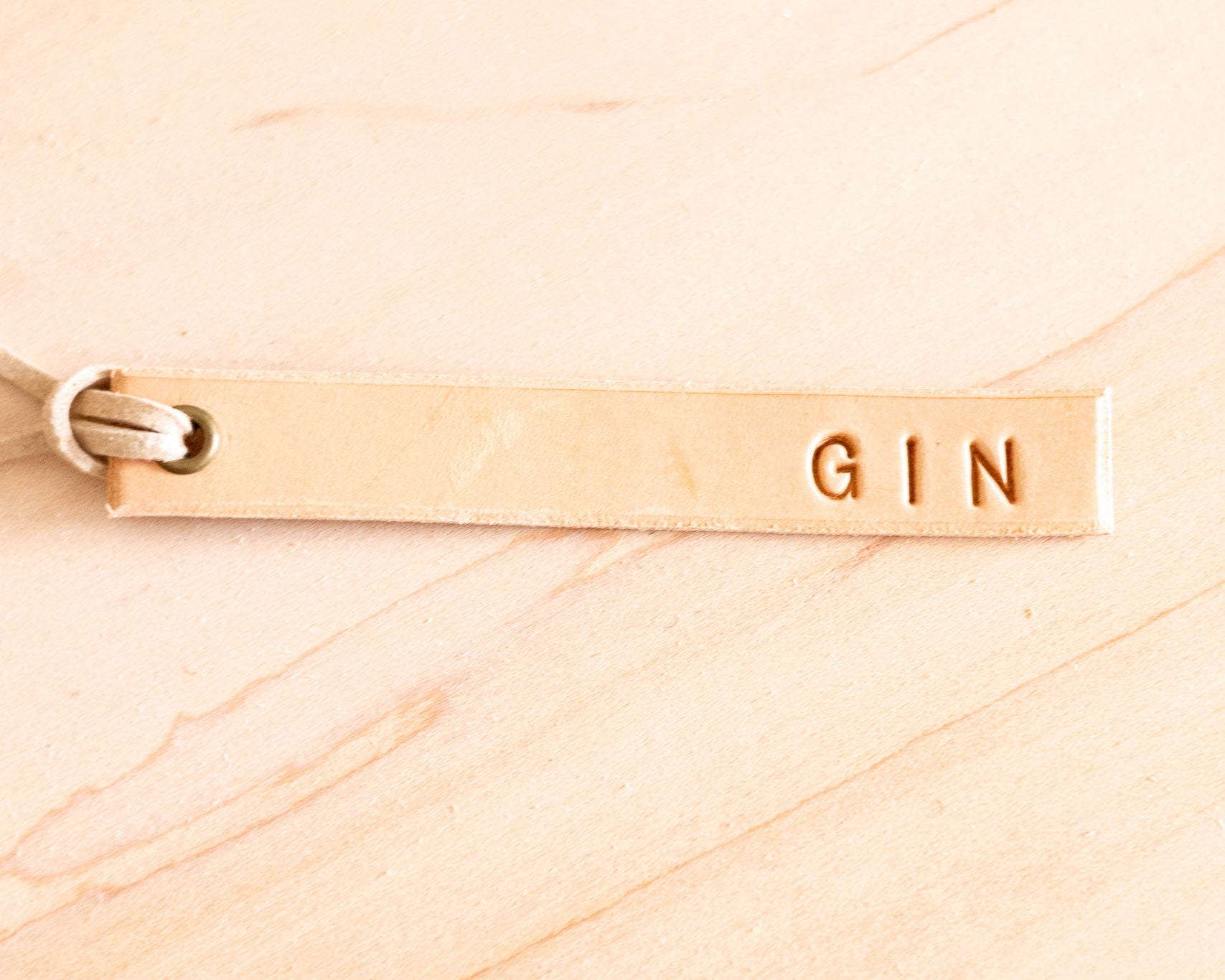 Leather 'GIN' tag on a wood background