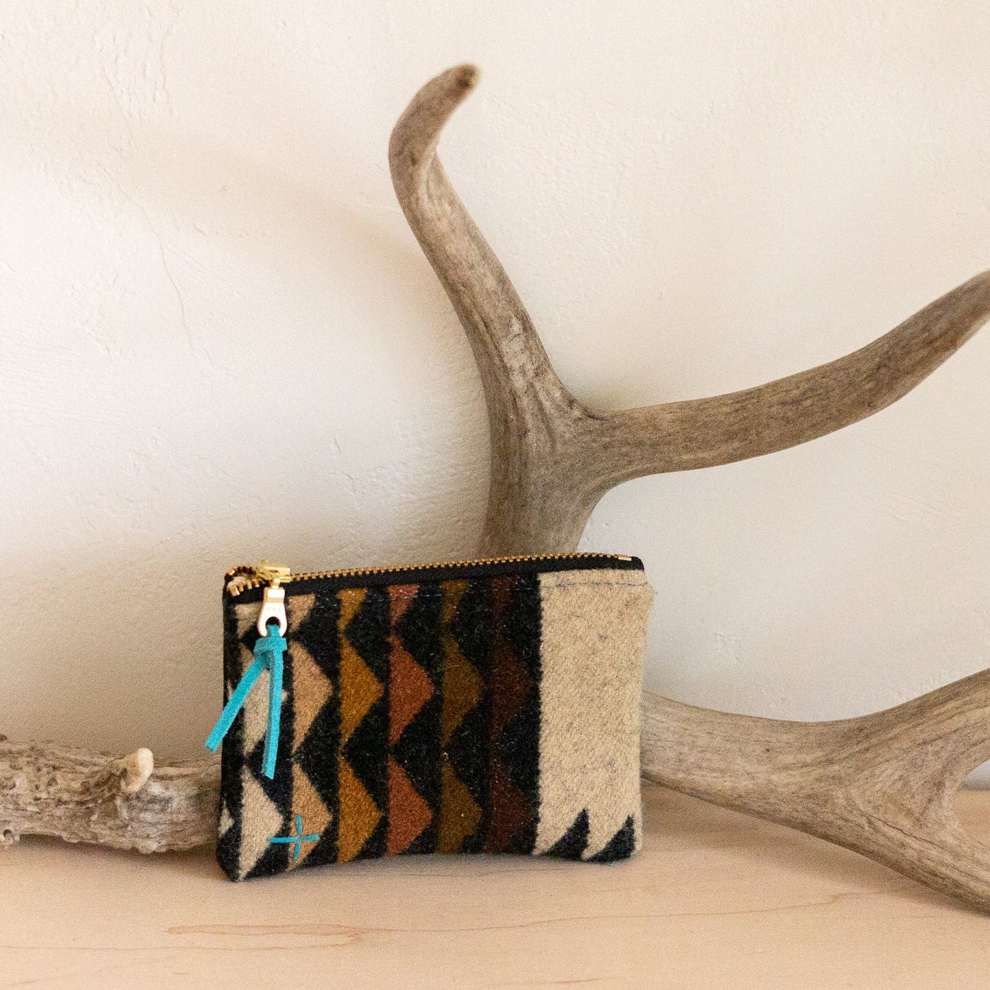 Small pouch with geometric pattern on a wooden surface with antlers in the background