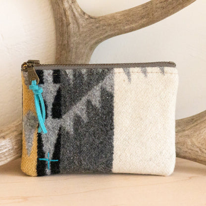 Woolen pouch with multicolor pattern on a surface with antlers in the background