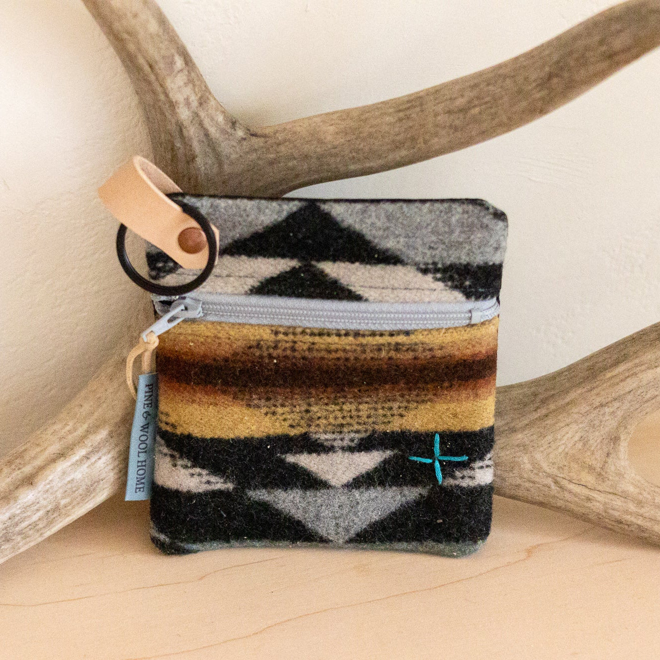 Small pouch with geometric pattern on a wooden surface with antlers in the background