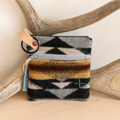 Small pouch with geometric pattern on a wooden surface with antlers in the background