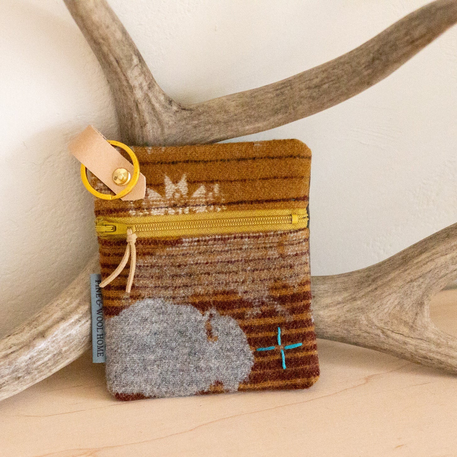 Small pouch with a zipper on a wooden surface with antlers in the background