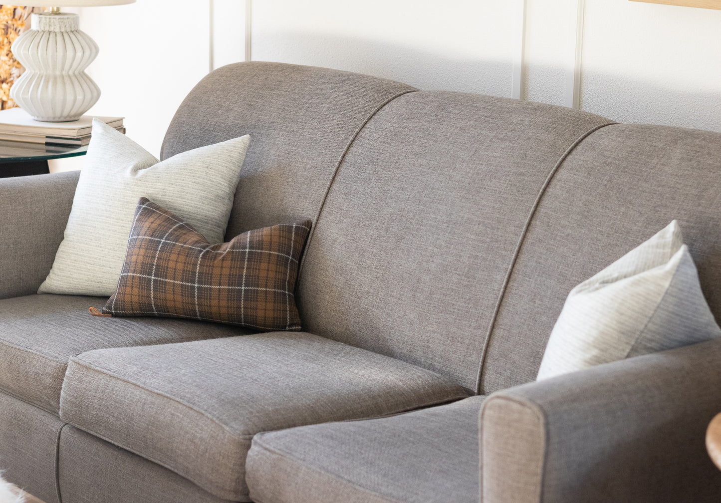 Gray sofa styled with two neutral stripe wool pillows and a charcoal plaid wool lumbar pillow cover
