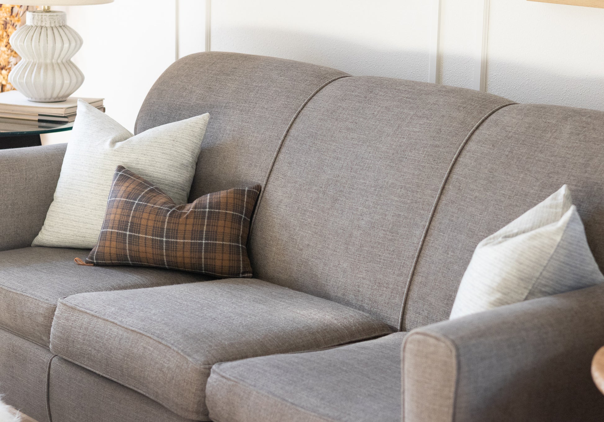 Gray sofa styled with two neutral stripe wool pillows and a charcoal plaid wool lumbar pillow cover