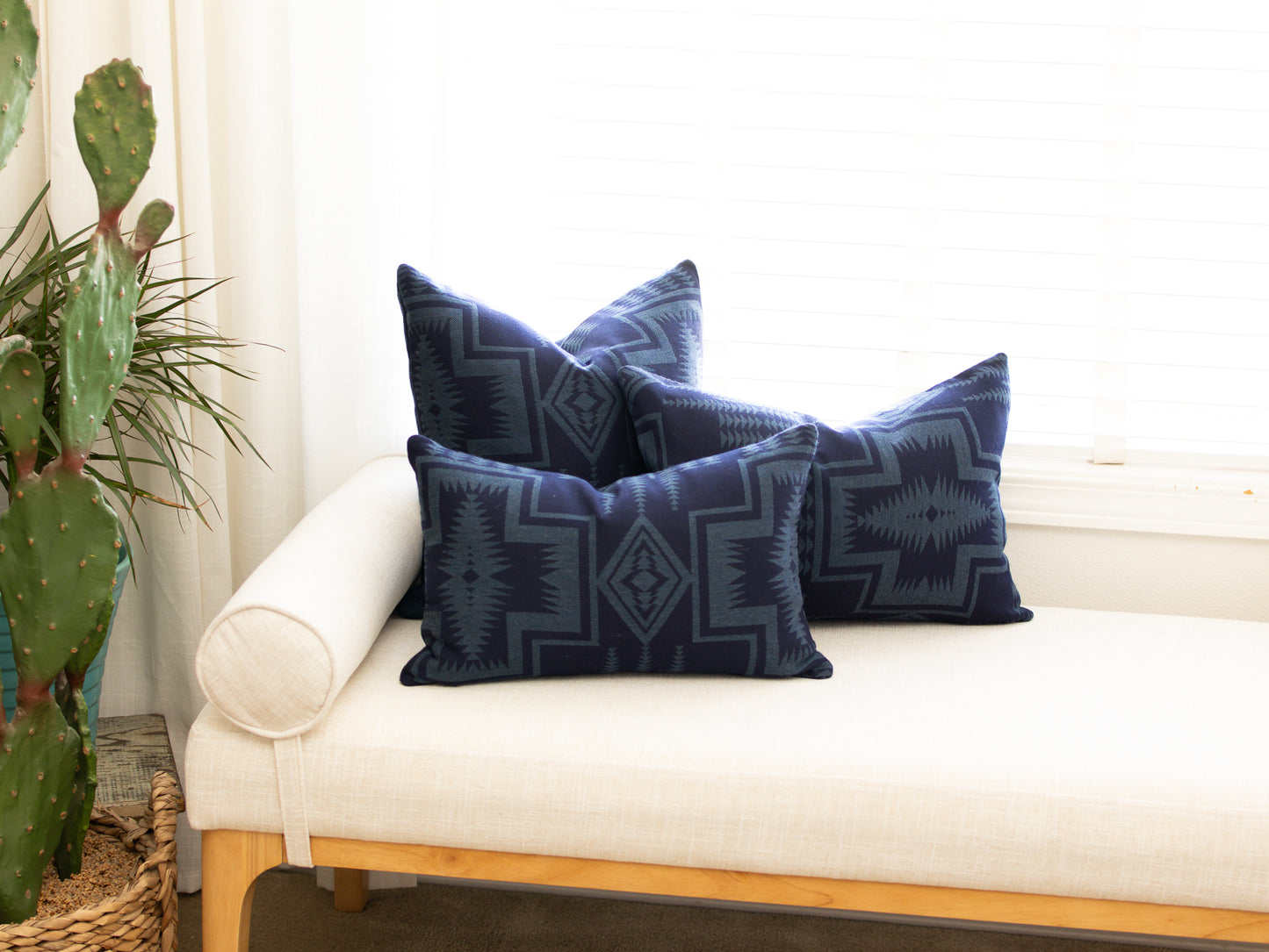 Blue patterned pillows on a white couch with a plant in the background