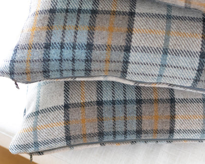 Plaid patterned fabric with blue, gray, and yellow colors on a white background