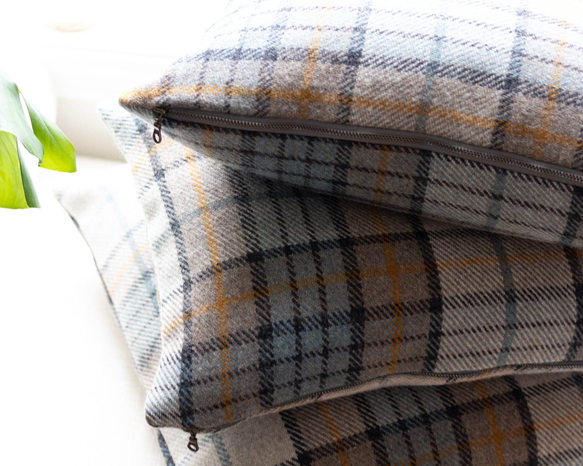 Plaid pillows stacked with a zipper on a white surface