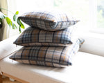 Stack of plaid cushions on a white sofa with a blurred background