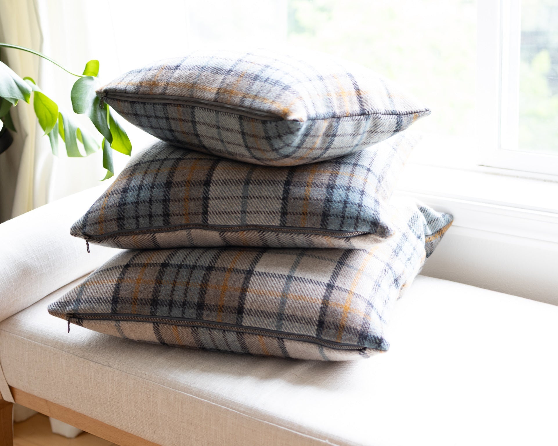 Stack of plaid cushions on a white sofa with a blurred background