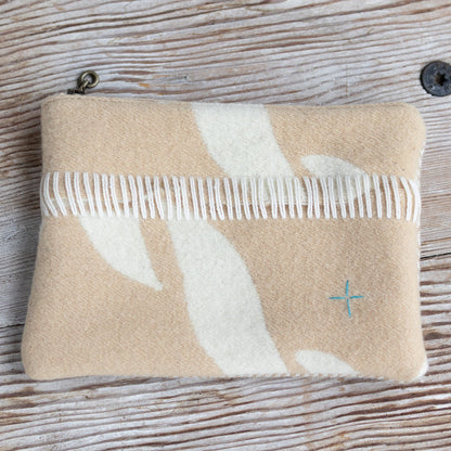Beige pouch with white floral design and a comb on a wooden surface