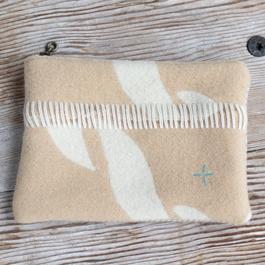 Beige pouch with white floral design and a comb on a wooden surface