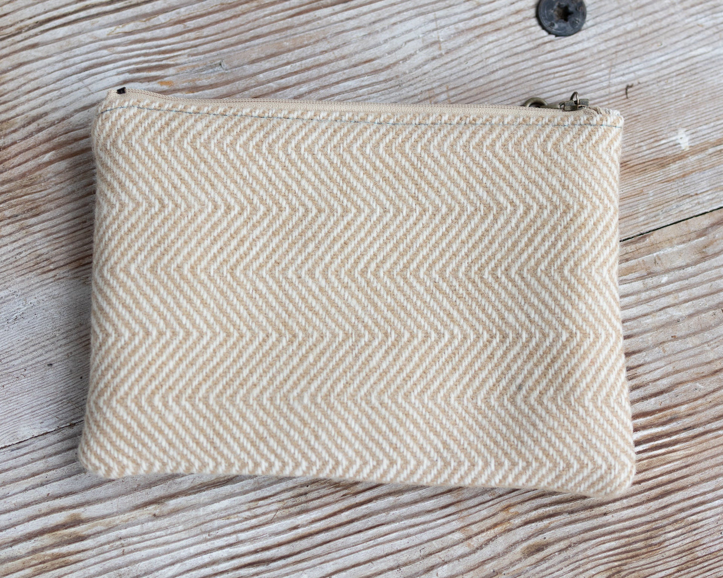 Beige herringbone patterned pouch on a wooden surface