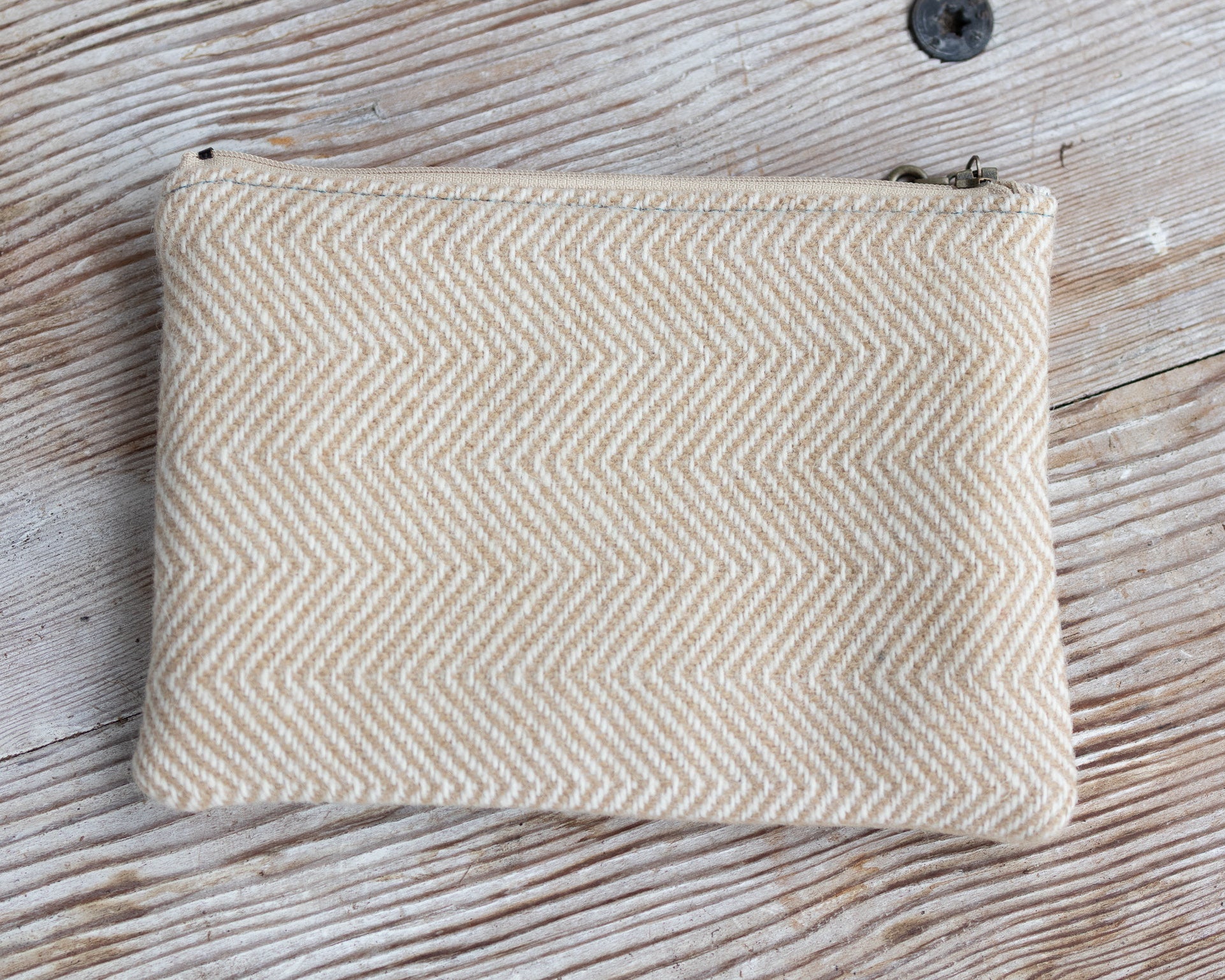 Beige herringbone patterned pouch on a wooden surface