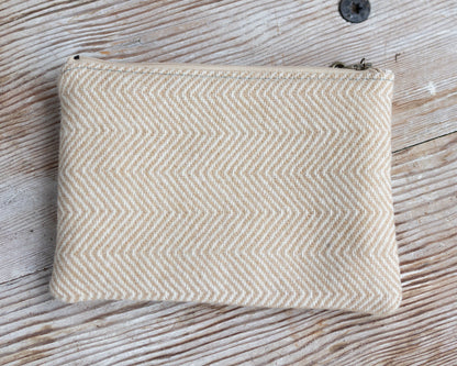 Beige herringbone patterned pouch on a wooden surface