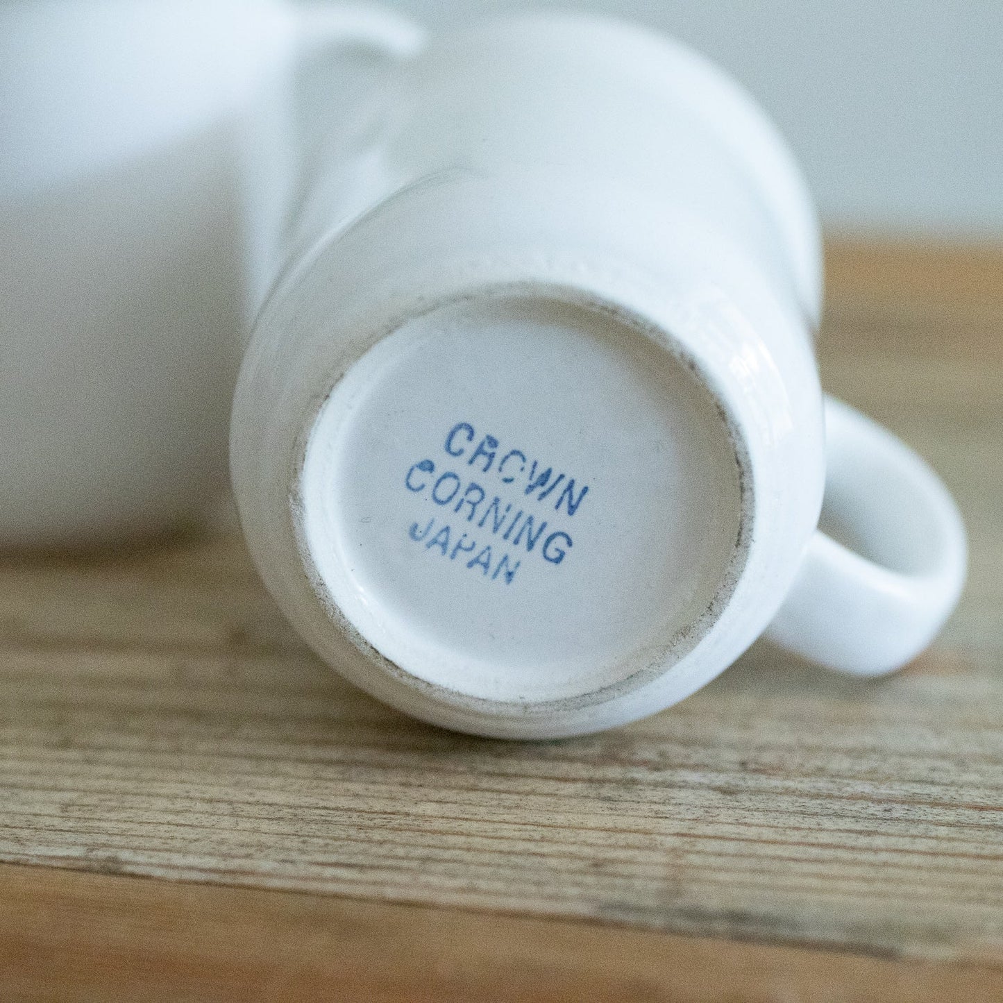 White mug with 'Crown Corning Japan' branding on a wooden surface
