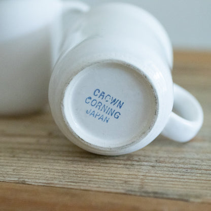 White mug with 'Crown Corning Japan' branding on a wooden surface
