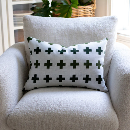 White armchair with a decorative pillow featuring green crosses on a white background.